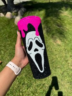 a hand holding up a black and pink can cooler with a ghost face on it