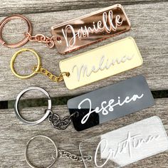 four personalized metal key chains on top of a wooden table