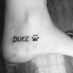 a black and white photo of a dog's paw with the word duke written on it