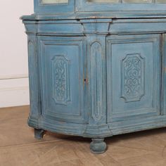 an old blue cabinet with glass doors on the top and bottom, sitting in a room