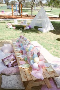 an outdoor picnic setting with pink and blue balloons on the table, plates and utensils