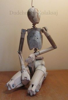 a white robot sitting on top of a wooden table next to a light brown wall