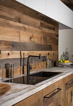 a kitchen with wooden walls and white counter tops, black faucet on the sink