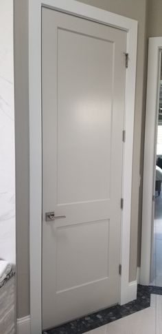 a white door in the middle of a room with marble flooring and walls behind it