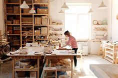 a woman is working in an art studio with lots of crafting supplies on the table