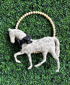 a white horse with a black bow on it's head in front of a green wall