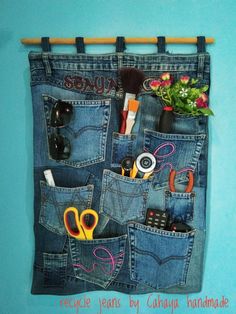 an old pair of jeans hanging on a wall with some scissors and other items in it