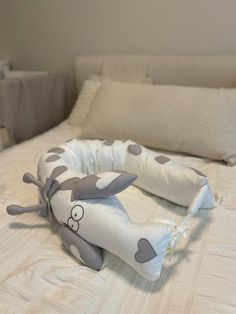 a stuffed animal laying on top of a bed next to pillows and pillowcases