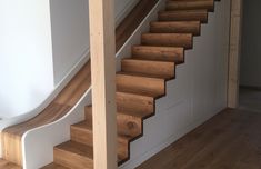 a wooden stair case next to a white wall