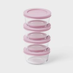 stack of glass containers with pink lids on white background, set of three for storage