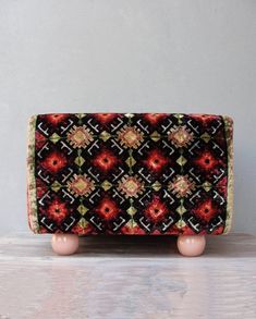 a small red and black purse sitting on top of a wooden table next to a white wall