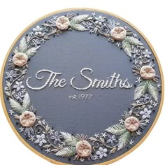 the smiths embroidery pattern is displayed in a hoop with flowers and leaves on it