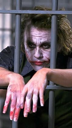 a man with his hands on the bars of a jail cell, wearing a costume