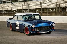 an old blue car driving down a race track