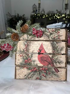 a wooden box with a cardinal on it and pine cones in the corner, sitting on a table