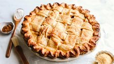 a pie sitting on top of a white table next to spoons and utensils