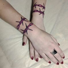 two girls with matching tattoos on their arms and wrist, both holding each other's hands