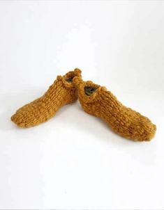 two brown knitted shoes sitting next to each other on top of a white surface