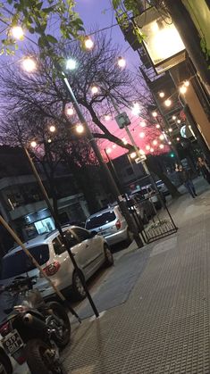 the street is lined with parked cars at night