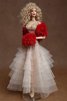 a barbie doll wearing a white and red dress with feathers on it's arms