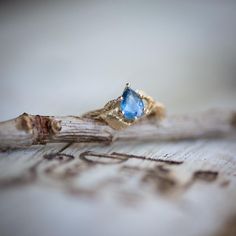 a blue stone ring sitting on top of a piece of wood