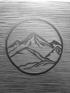 a wooden plaque with mountains in the middle and a circular design on it's side