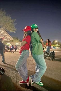 two young people are standing on skateboards in the street at night, one is hugging the other