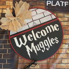 a sign that says welcome muggles hanging on a brick wall next to a pair of eyeglasses