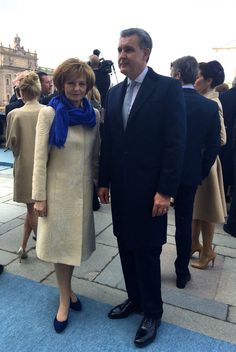 a man and woman standing next to each other on a blue carpet in front of people