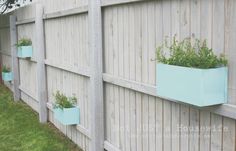 three blue planters on the side of a wooden fence