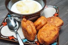 some fried food on a plate with a bowl of yogurt