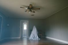 an empty room with a ceiling fan and white cloth draped over the top of it