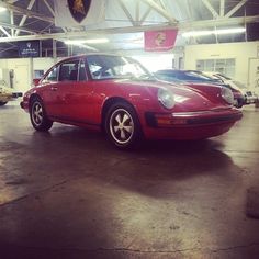 a red car parked in a garage next to other cars