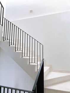 a white staircase with black railing and handrail