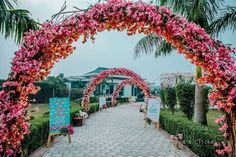 an archway decorated with pink flowers and greenery