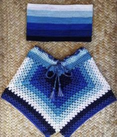 a blue and white crocheted blanket next to a hat on top of a woven mat