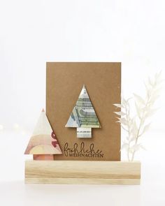 a card with a christmas tree made out of scrapbook paper on top of a wooden block