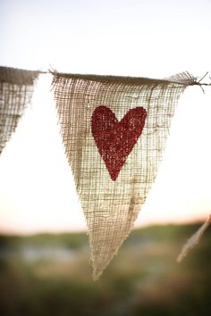 two red hearts are hanging from a string on the clothes line, with grass in the background