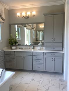 a large bathroom with double sinks and gray cabinets