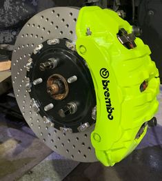 a close up of a yellow brake on a vehicle's front wheel and rotors