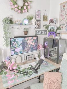 a computer desk topped with two monitors next to a pink flowered wall hanging on the wall