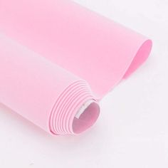 a roll of pink colored paper on a white surface with the end rolled up in half