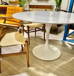 a table and chairs in a room with wood flooring on one side and white marble top on the other