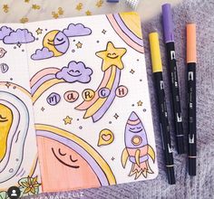 an open notebook with drawings and pens on it next to some other items such as markers