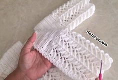 a hand is holding an object made out of white knitted material and crochet