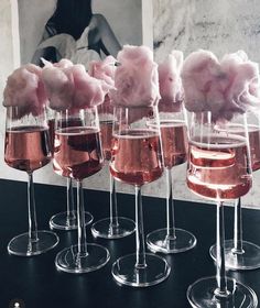 four wine glasses filled with pink cotton candy on top of a black table next to each other