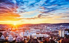 the sun is setting over a city with tall buildings and hills in the back ground