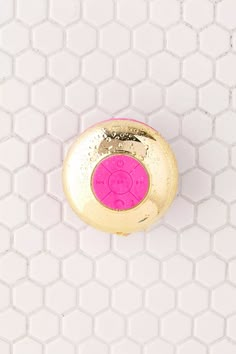 a pink and gold knob on a white tiled wall