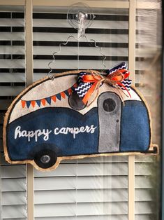 a happy camper door hanger hanging on a window sill with the words happy campers painted on it