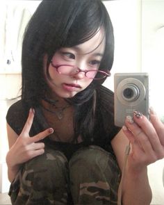 a woman with glasses taking a selfie in front of a mirror while holding a camera